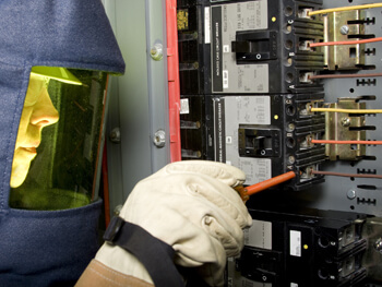 Technician servicing an electrical box with safety gear on