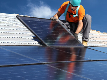 Man installing solar energy units on a rooftop